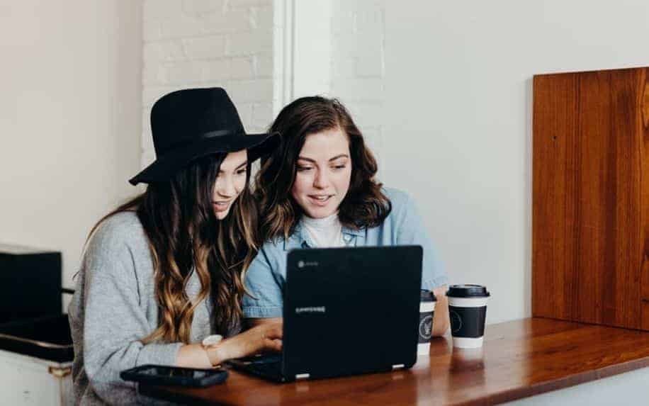 two girls sharing a laptop