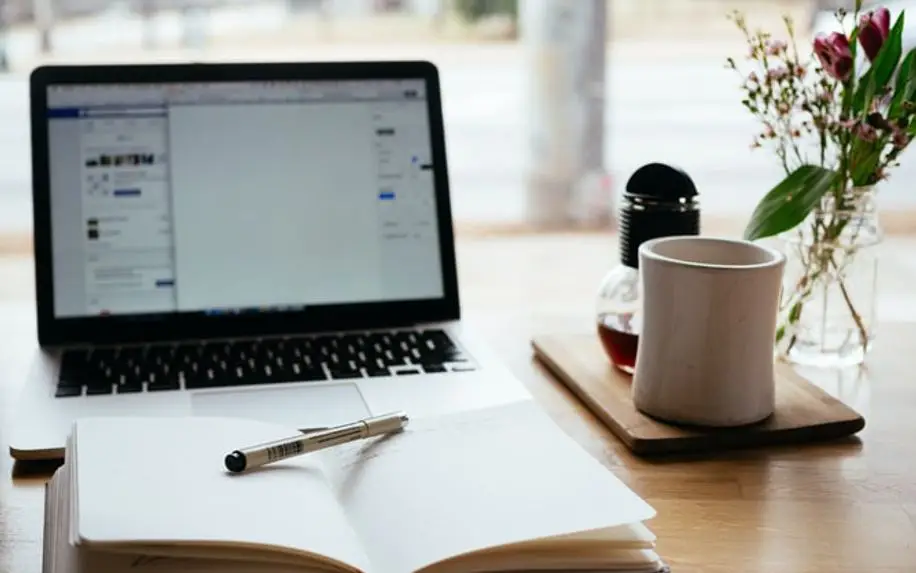 book and pen open on top of laptop