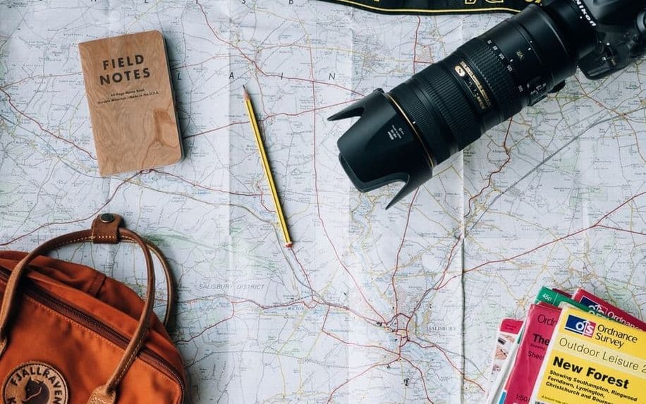 travel bag and camera lying on an open map