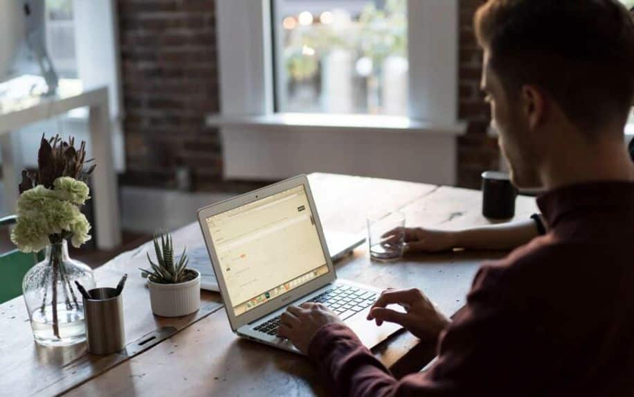 Man typing up first wordpress blog on laptop at table