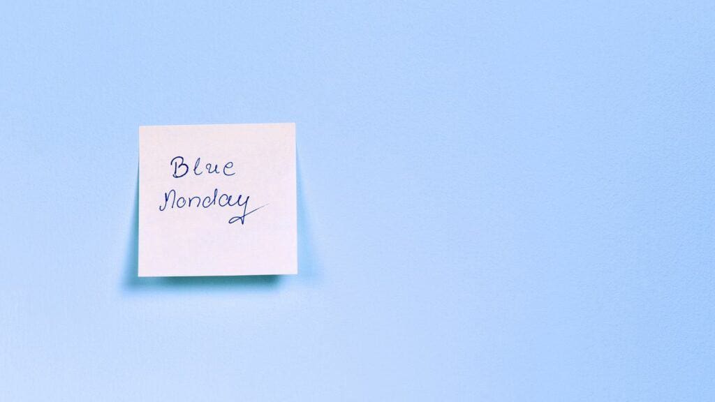 blue background, white sticky note with 'Blue Monday' written on it