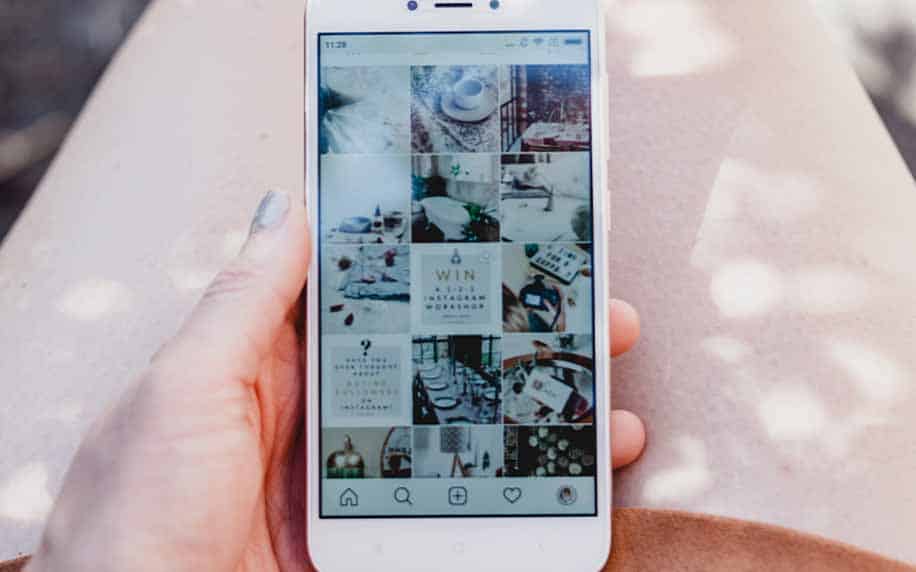 a marketer holding a phone with a Instagram grid open, browsing it