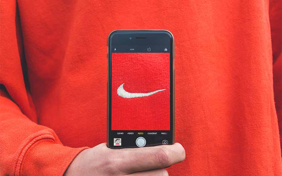 man holding a phone taking a picture of the nike logo on his jumper showing brand awareness