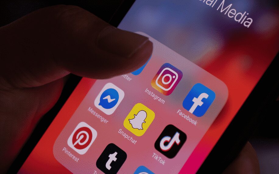 hand holding phone with social media apps on screen