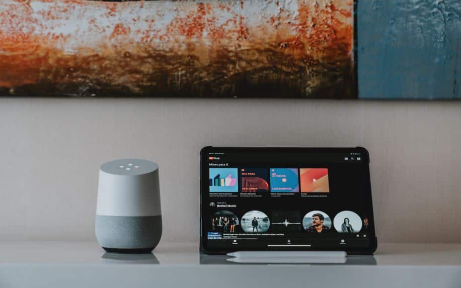 A photo of a Google Home speaker and tablet on a desk.
