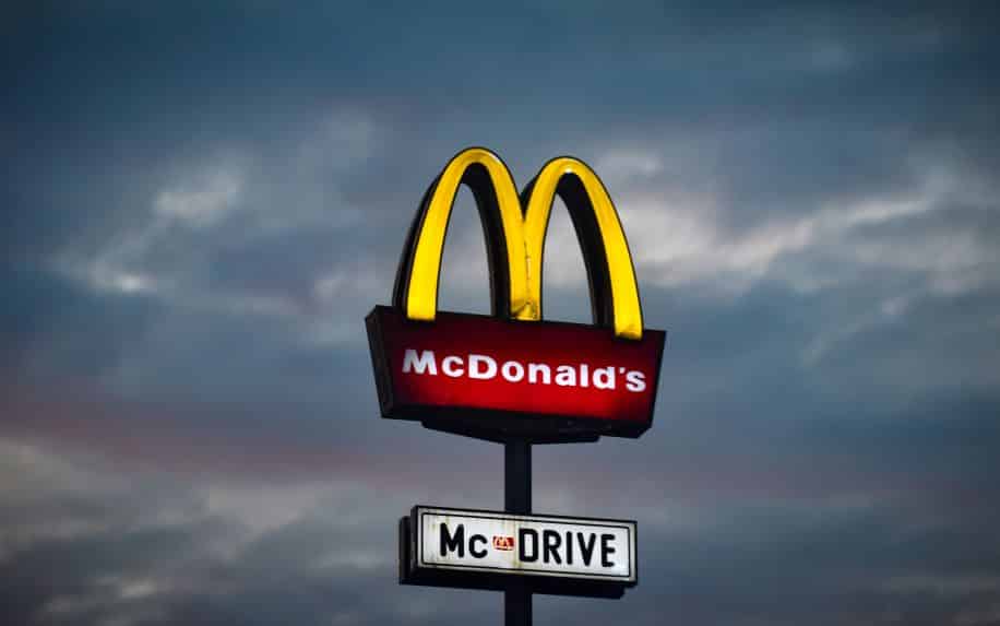 An illuminated McDonald's sign on a cloudy evening