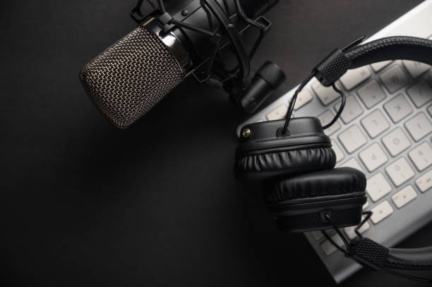Podcast Software - headphones, mic and keyboard on a black desk