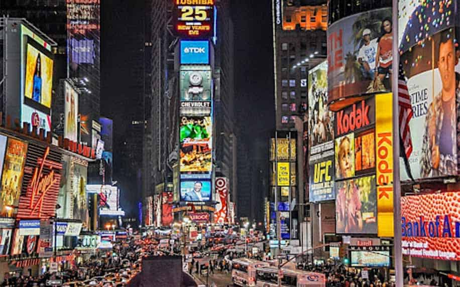 Influencer Marketing: A busy nighttime scene of Times Square in New York City, filled with bright, colorful electronic billboards showcasing influencer marketing campaigns, advertisements, crowds of people, and cars on the street.