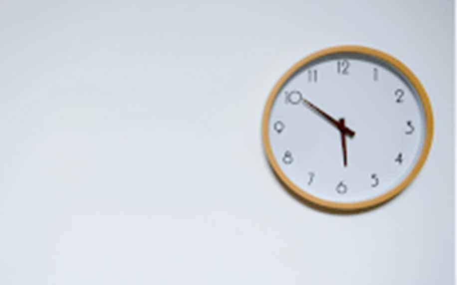 Influencer Marketing: A round wall clock with a light wooden frame, perfect for influencer marketing backdrops, is mounted on a plain white wall. The clock shows the time as 10:10.