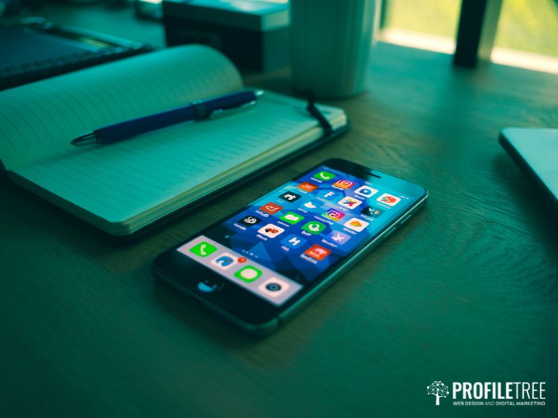 Social media training tools laid out on a desk including a smartphone showing social media apps and a notebook for planning