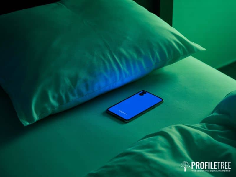 Social media and stress and sleep disruption — phone screen glow on a bed at night