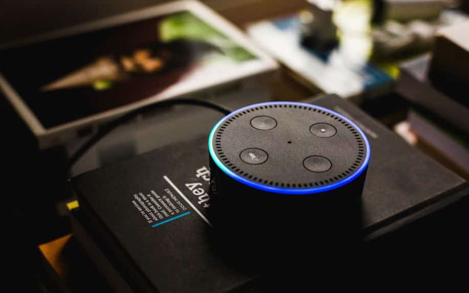 A black Amazon Alexa speaker sitting on top of a stack of books.