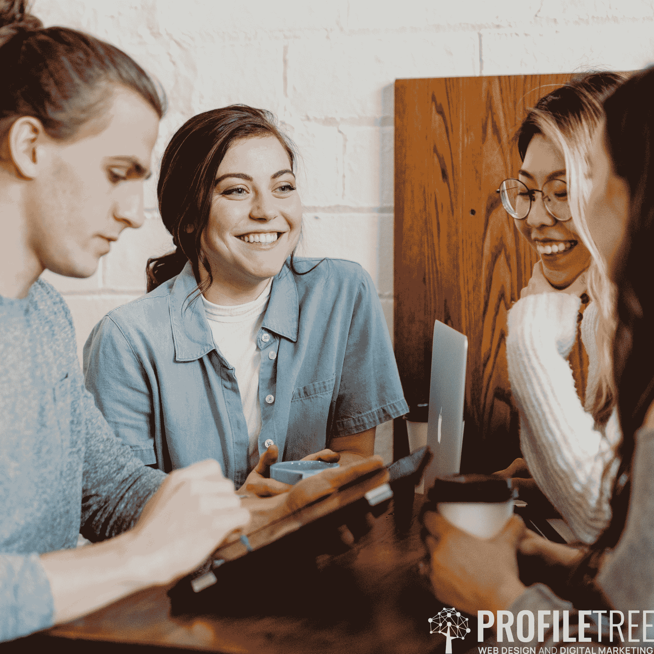 An image of friends laughing while looking at a phone